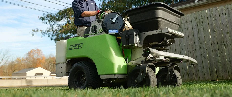 Man on a spreader machine in Hatfield, PA, fertilizing a lawn.