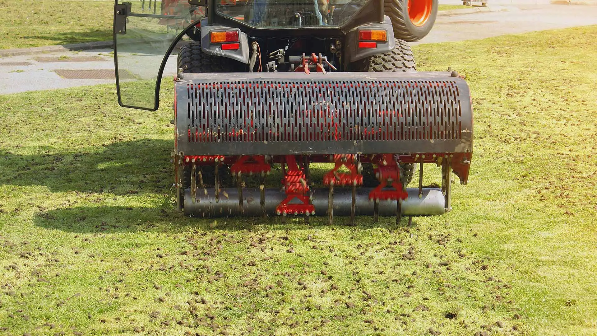 A professional is aerating a lawn using a large aearation vehicle.