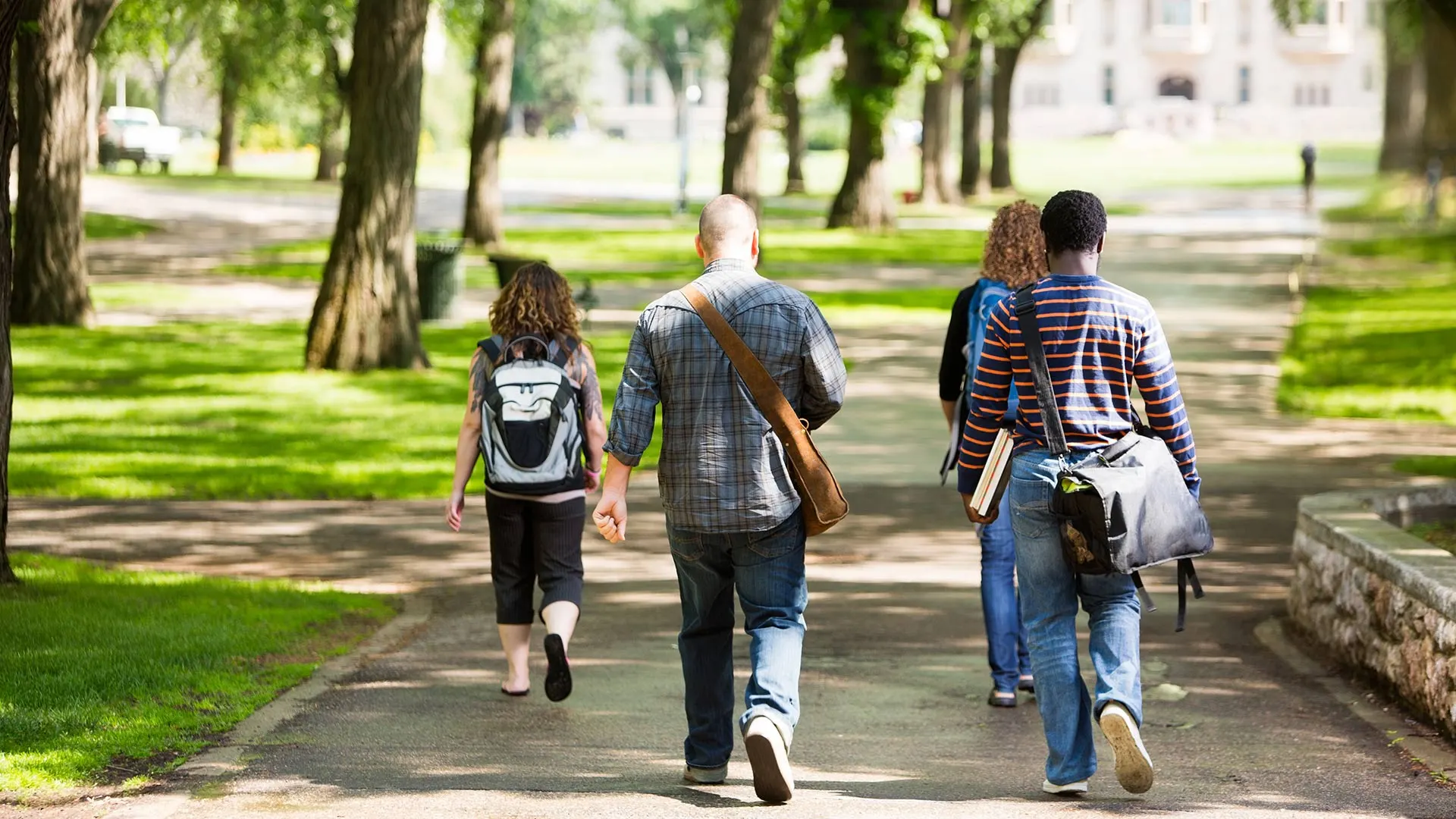 Students walking through a college campus on a sunny afternoon.