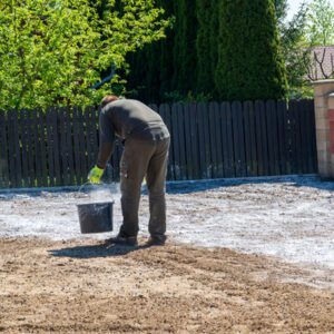 man adding lime to soil in back yard